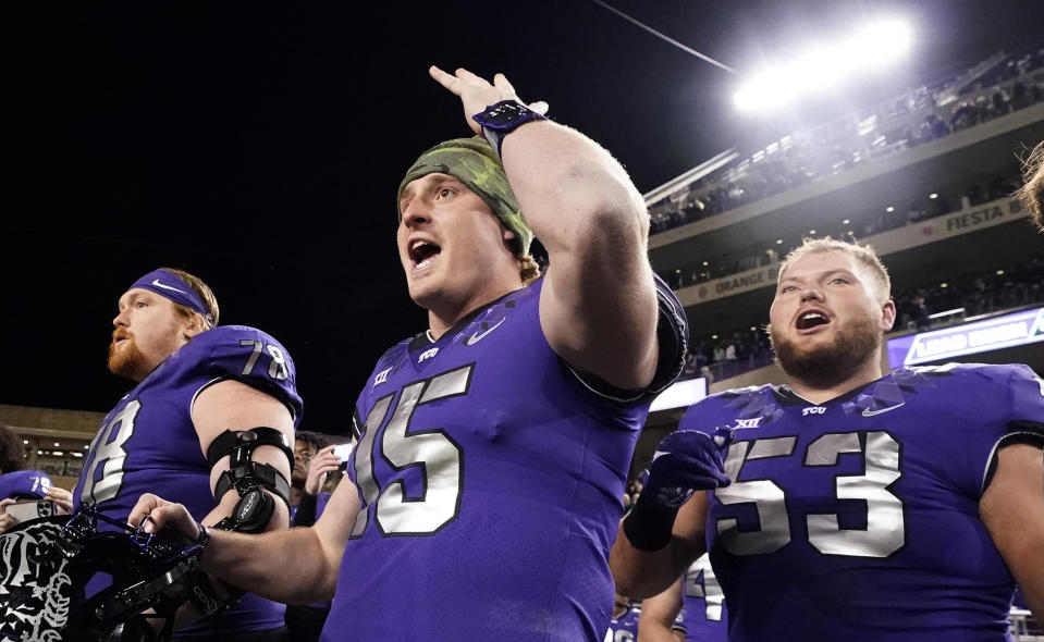 TCU quarterback Max Duggan (15) reacts on the sidelines with teammates guards John Lanz (53) and Wes Harris during the second half of an NCAA college football game against Iowa State in Fort Worth, Texas, Saturday, Nov. 26, 2022. TCU won 62-14. (AP Photo/LM Otero)