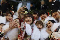 In this Jan. 13, 2020, photo, a group of women pauses for a selfie during a Coming-of-Age ceremony at Tokyo Disneyland in Urayasu, near Tokyo. Held annually on the second Monday of January, Coming of Age Day is a special time for these young adults. (AP Photo/Jae C. Hong, File)