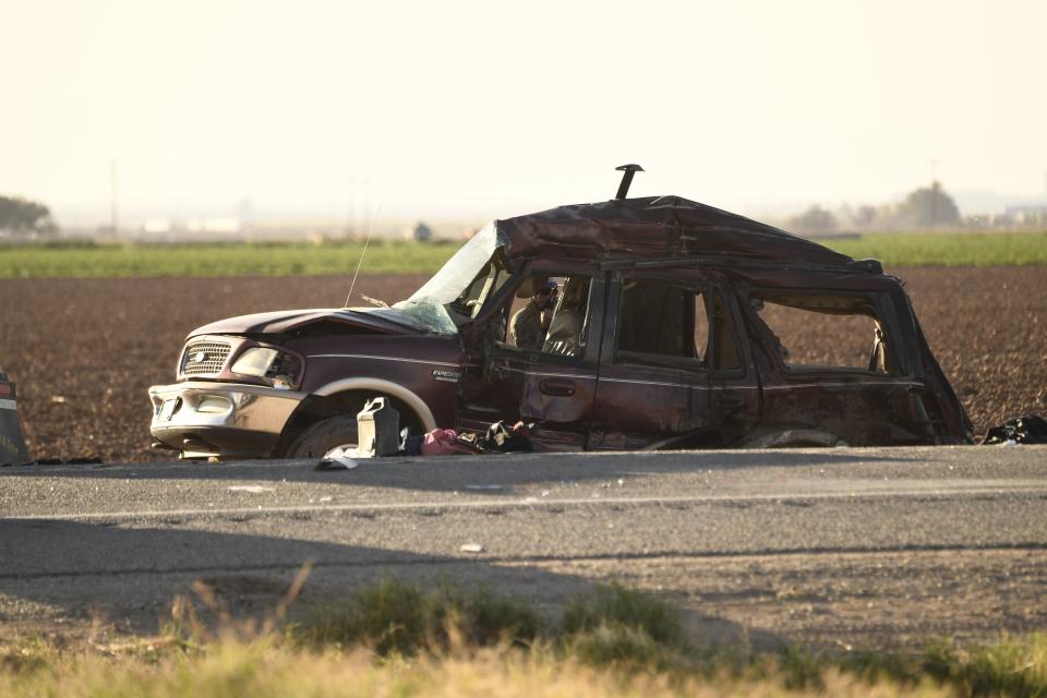 A California Highway Patrol Border Division officer looks inside an SUV that crashed with a semi-truck full of gravel near Holtville, California on March 2, 2021. - At least 13 people were killed in southern California on Tuesday when a vehicle packed with passengers including minors collided with a large truck close to the Mexico border, officials said. (Photo by Patrick T. FALLON / AFP) (Photo by PATRICK T. FALLON/AFP via Getty Images)