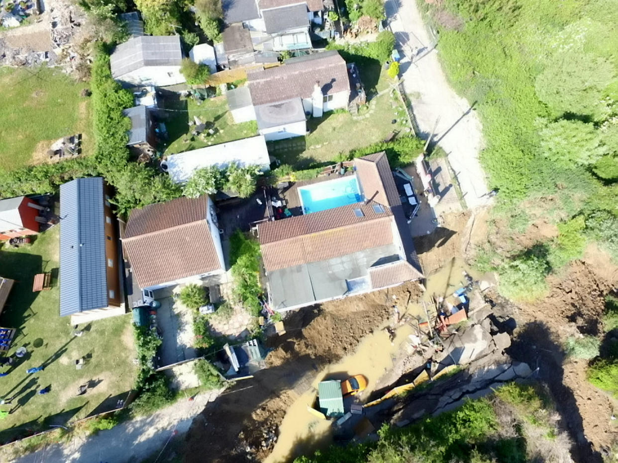  Shocking new photos show a house teetering on the edge of a cliff, after a dramatic collapse forced the evacuation of 20 houses in Eastchurch, Kent. May 31 2020. See SWNS story SWNNcliff. Shocking new photos show a house teetering on the edge of a cliff, after a dramatic collapse forced the evacuation of 20 houses. Drone footage shows a home - in Eastchurch, Kent - hanging off the edge off the cliff, with cars also tumbling down the slope. Up to three metres of land in front of the property fell away on Friday night after years of erosion. While all but two of the households were able to return home yesterday, several were left without electricity as a result of the incident - and one is at serious risk of collapsing into the sea.