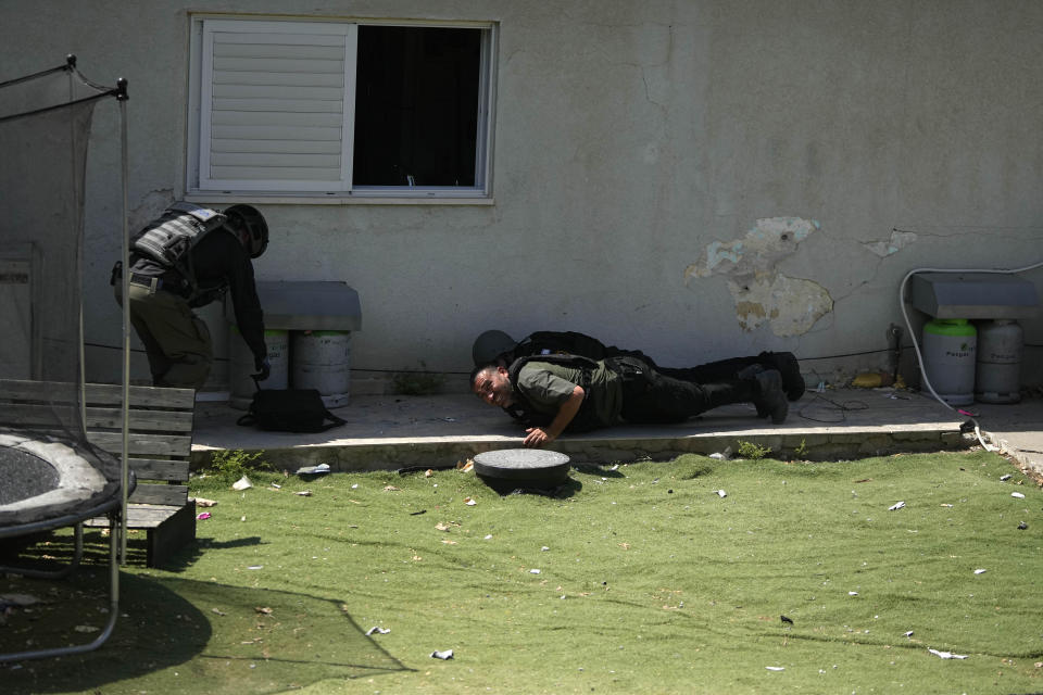 Israeli security forces take cover during an air raid siren warning of incoming rockets fired from the Gaza Strip, in Sderot, southern Israel, near the Gaza border, Wednesday, May 10, 2023. Israeli authorities say Palestinian militants in the Gaza Strip have launched rockets toward southern Israel. Wednesday's launch comes a day after Israeli airstrikes killed three militant leaders and at least 10 civilians. (AP Photo/Tsafrir Abayov)