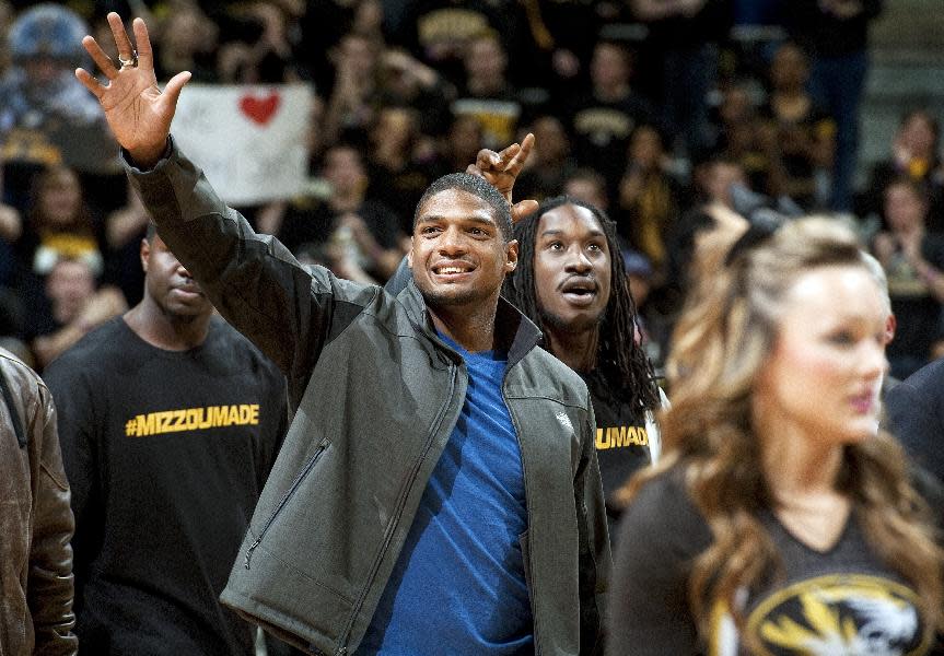 Missouri's All-American defensive end Michael Sam waves to the crowd during the Cotton Bowl trophy presentation at halftime of an NCAA college basketball game between Missouri and Tennessee, Saturday, Feb. 15, 2014, in Columbia, Mo. Sam came out to the entire country Sunday, Feb. 9, and could become the first openly gay player in the NFL. (AP Photo/L.G. Patterson)