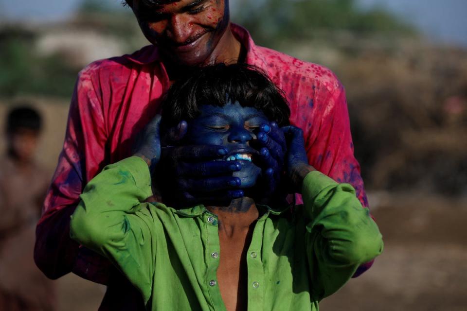 Red chilli pepper farmers smear colour on their face as they celebrate Holi (Reuters)