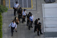 Residents past by police and security personnel preparing for duty outside the Evergrande headquarters in Shenzhen, China, Friday, Sept. 24, 2021. Things appeared quiet at the headquarters of the heavily indebted Chinese real estate developer Evergrande, one day after the day it had promised to pay interest due to bondholders in China. (AP Photo/Ng Han Guan)