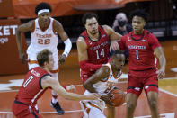 Texas guard Matt Coleman III (2) grabs a rebound as Texas Tech's Mac McClung, Marcus Santos-Silva and Terrence Shannon Jr., from left, defend during the first half of an NCAA college basketball game Wednesday, Jan. 13, 2021, in Austin, Texas. (AP Photo/Eric Gay)