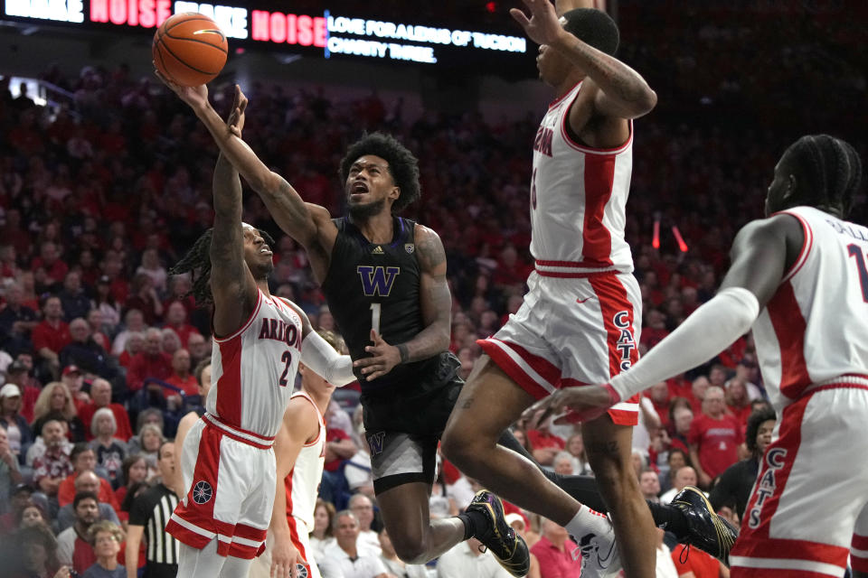 Washington forward Keion Brooks Jr. (1) drives between Arizona guard Caleb Love (2) and forward Keshad Johnson (16) during the first half of an NCAA college basketball game, Saturday, Feb. 24, 2024, in Tucson, Ariz. (AP Photo/Rick Scuteri)