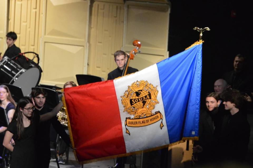 Students at O’Fallon Township High School hold a flag commemorating the award at a May concert, where the band program celebrated the achievement. O'Fallon Band Boosters
