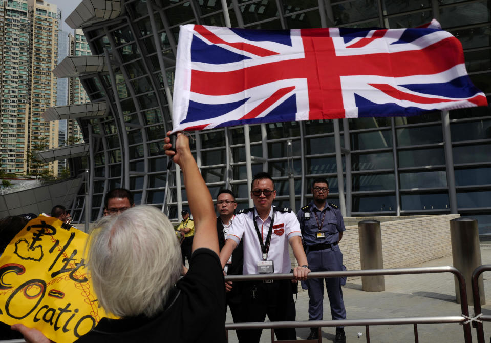 A woman waves a British flag outside the Western Kowloon Station during a protest against the opening ceremony of the Hong Kong Express Rail Link in Hong Kong, Saturday, Sept. 22, 2018. Hong Kong has opened a new high-speed rail link to inland China that will vastly decrease travel times but which also raises concerns about Beijing's creeping influence over the semi-autonomous Chinese region. (AP Photo/Vincent Yu)