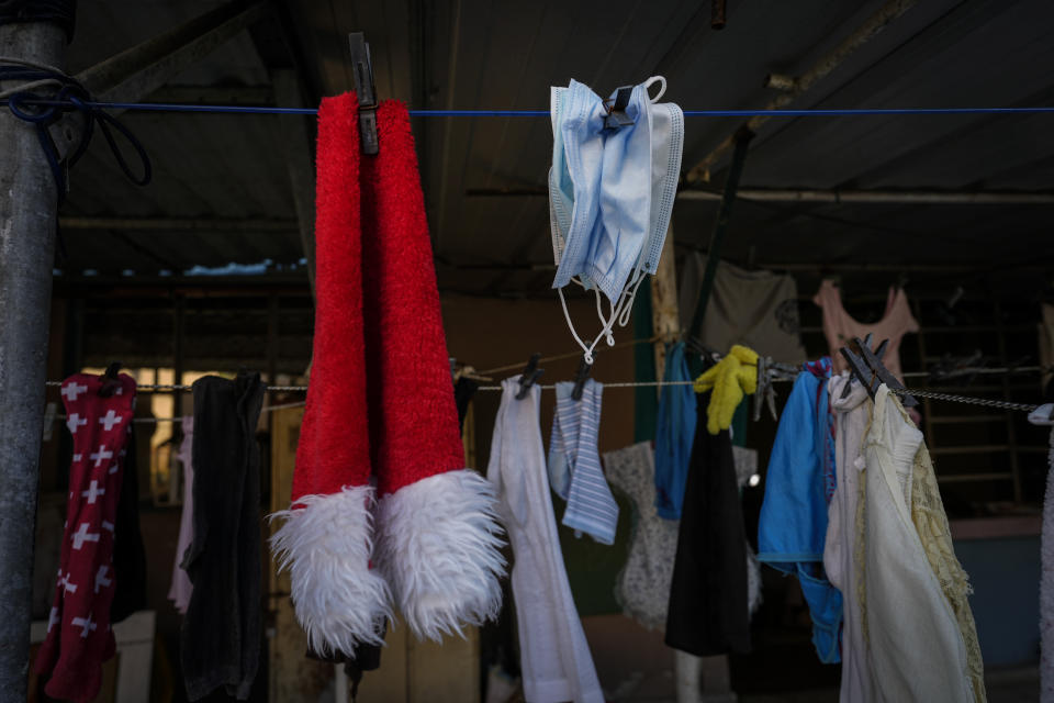 Several used non-reusable masks hang on a clothesline to dry after being washed, at the home of Marylin Alvarez, where she works on a client's nails in the Bahia neighborhood of Havana, Cuba, Wednesday, May 18, 2022. During President Barack Obama's administration, Alvarez began transforming part of her house into a tiny cafe with the help of money sent by a cousin living in the U.S., but it fell apart when President Donald Trump's administration tightened the embargo and sharply restricted money transfers to Cuba in late 2020, which turned Alvarez to a less costly form of making money for her family — giving manicures. (AP Photo/Ramon Espinosa)