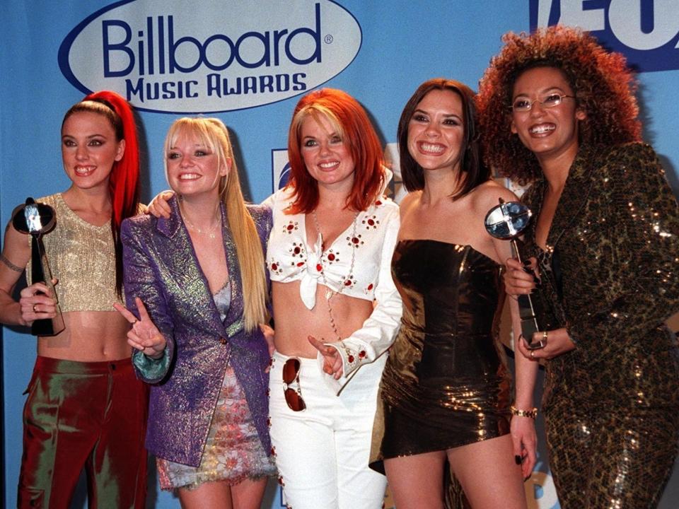 Melanie C, Emma Bunton, Geri Halliwell, Victoria Beckham, Mel B smiling at an awards show.