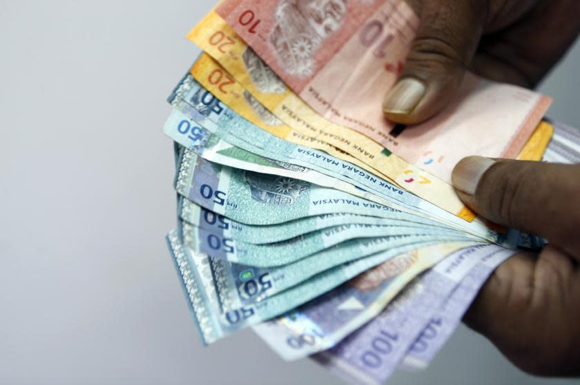 An employee counts money as he poses inside a money exchange centre in Kuala Lumpur October 22, 2013. — Reuters pic