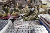 Washington National Guard soldiers and airmen pack food at the Nourish Pierce County warehouse in response to the coronavirus outbreak Friday, April 3, 2020, in Lakewood, Wash. National Guard members will be packing food at the warehouse five days a week for delivery to multiple food banks, taking over for volunteers who normally pack several hundred boxes a day. The need for food at the pantries in the area is expected to at least double in the coming weeks. (AP Photo/Elaine Thompson)