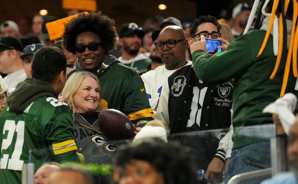 Fans pose with a football tossed into the stands by Green Bay Packers running back Aaron Jones after he scored a touchdown during the first quarter of the wild card playoff game against the Dallas Cowboys on Sunday, January 14, 2024 at AT&T Stadium in Arlington, Texas.