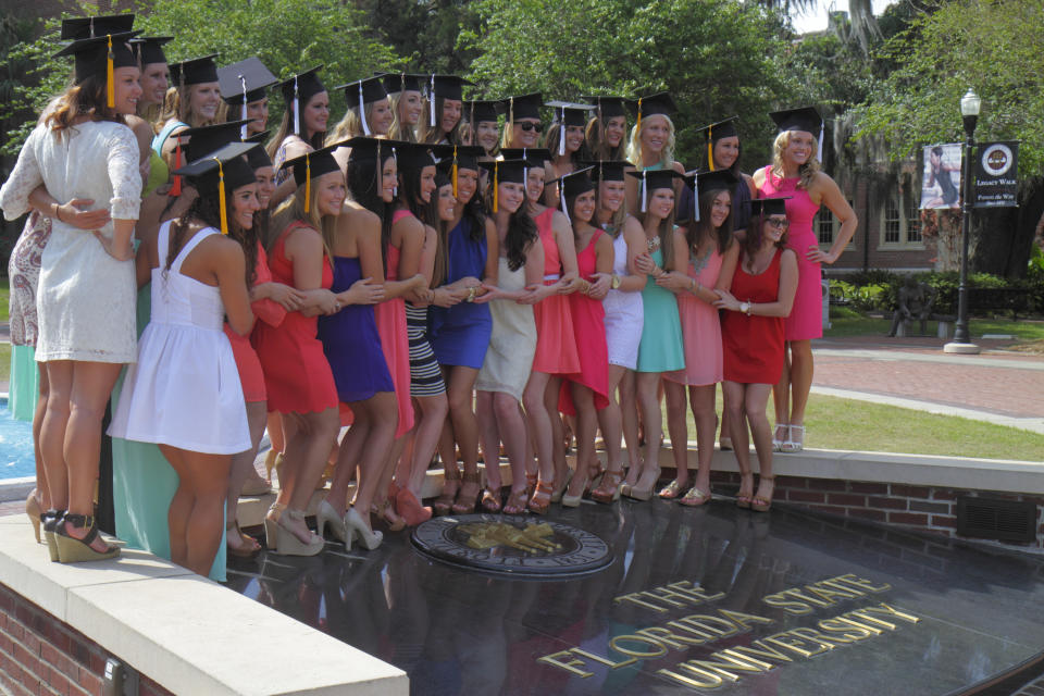 A group of sorority sisters posing together in their graduation caps and dresses