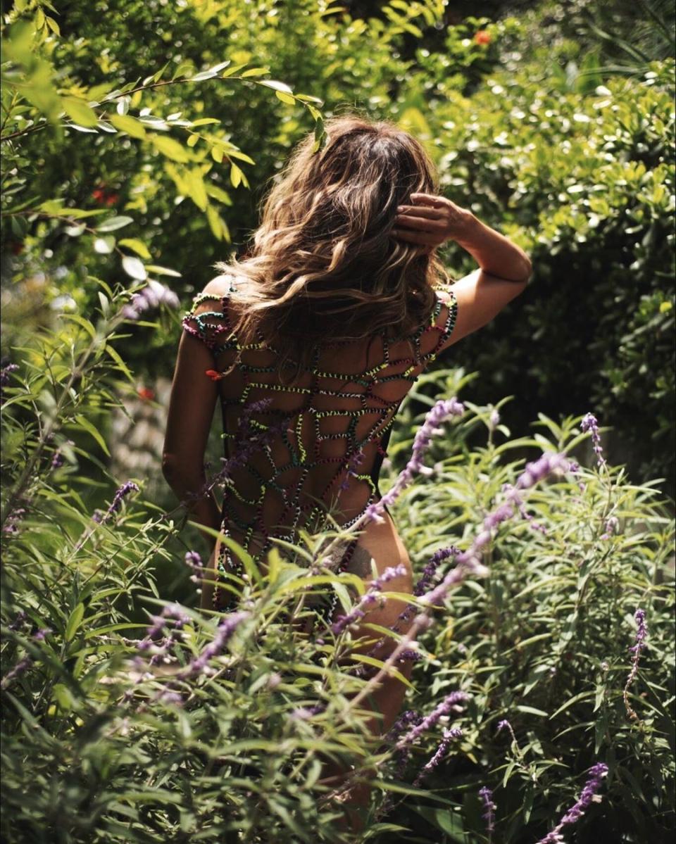 Halle Berry poses nude under mesh netting in a garden