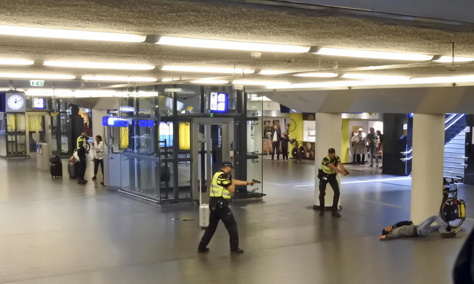 Dutch police officers point their guns at a wounded 19-year-old man who was shot by police after stabbing two people in the central railway station in Amsterdam, the Netherlands, Friday Aug. 31, 2018. Police investigators in Amsterdam included an extremist attack as a possible motive for the stabbings of two people at a busy railway station Friday as authorities in the Dutch capital reported that the suspect shot by police is an Afghan citizen. (AP Photo)