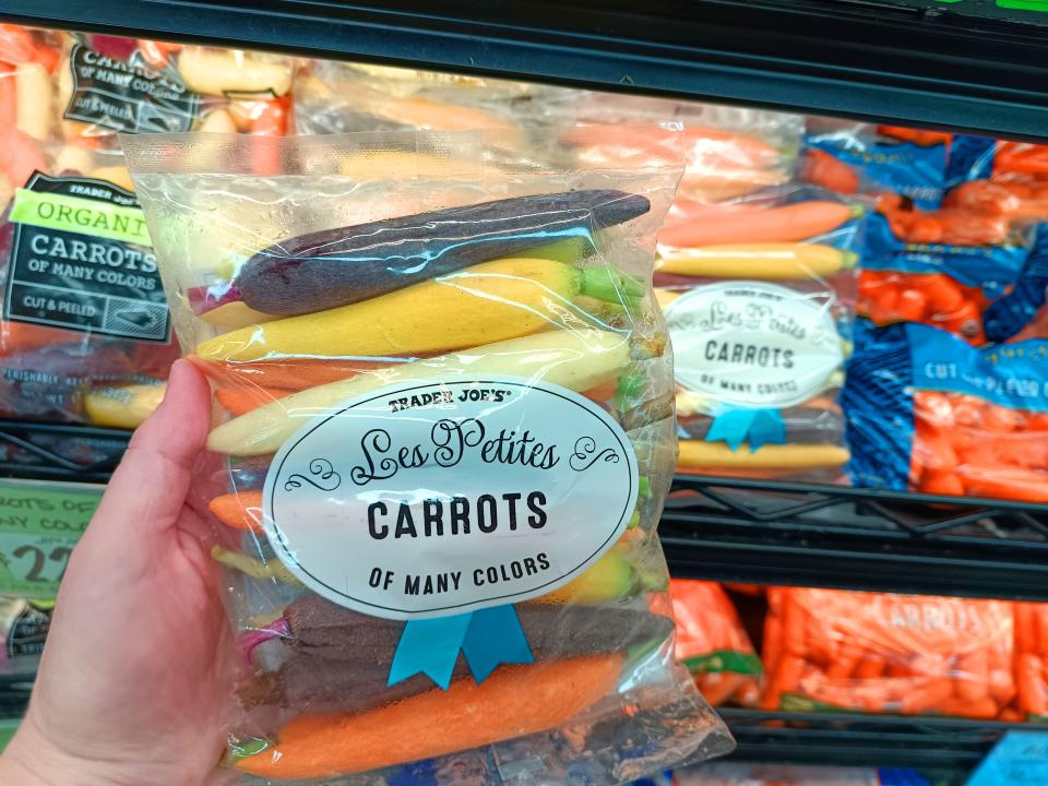 Hand holding pack of colorful carrots at Trader Joe's