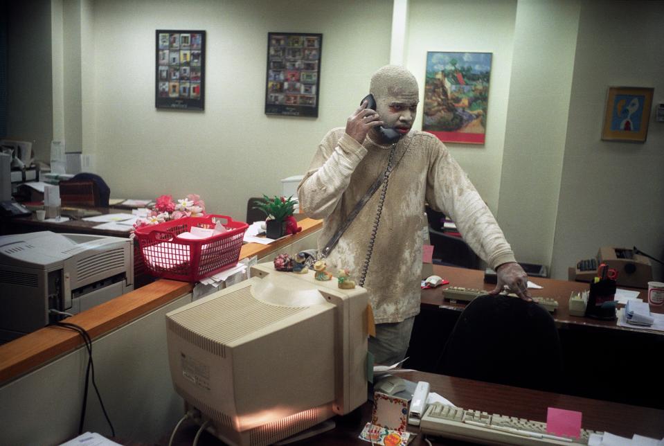 A man on the phone in an office, covered with dust.