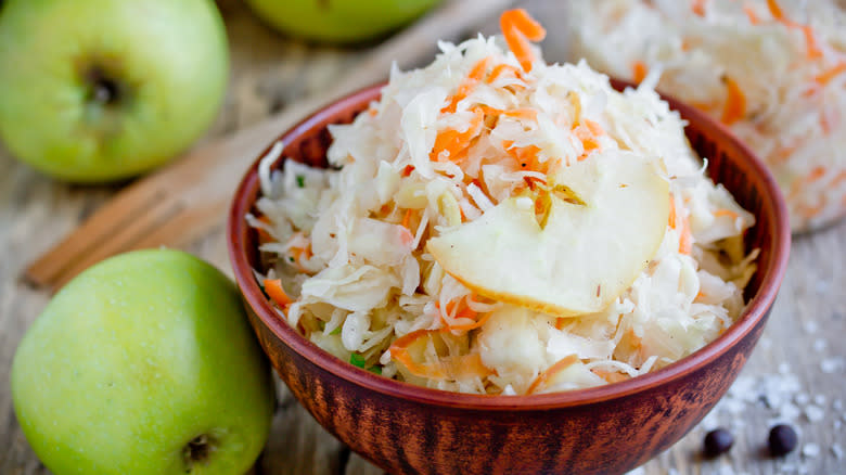 bowl of sauerkraut with green apples on table