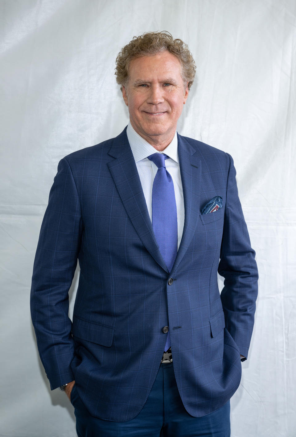 Will Ferrell in a suit and tie, standing and smiling