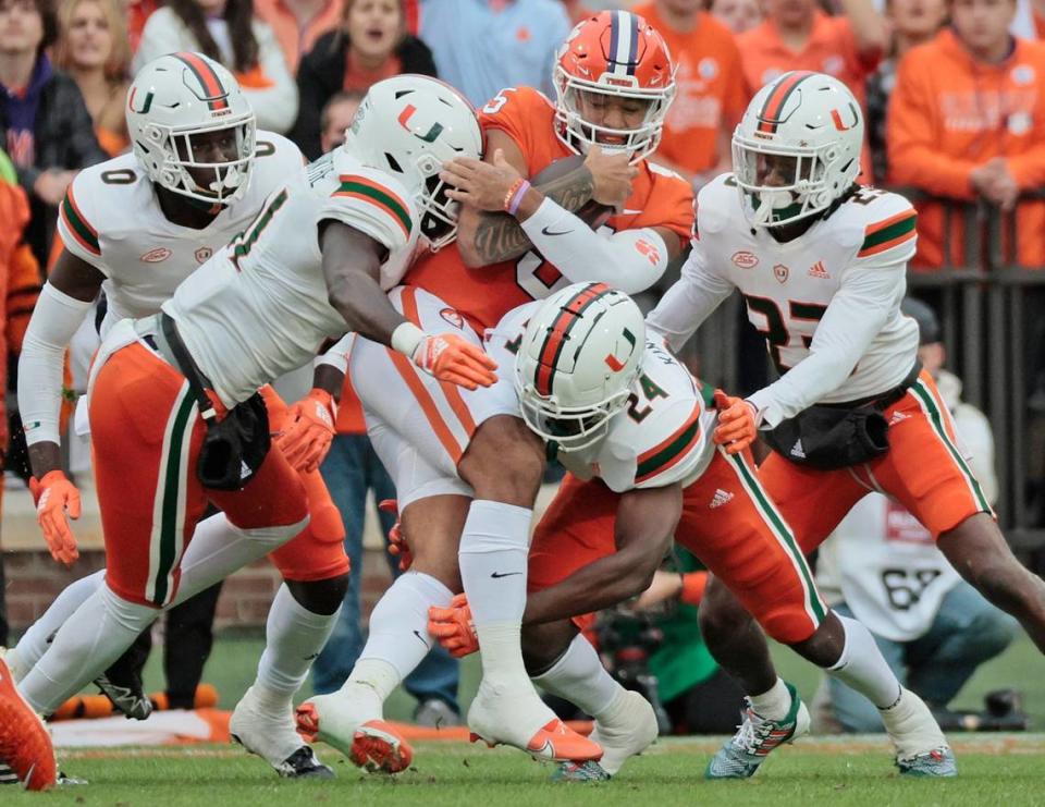 Miami Hurricanes linebacker Wesley Bissainthe (31), safety Kamren Kinchens (24), and cornerback Te’Cory Couch (23) gang tackle quarterback DJ Uiagalelei (5) in the first half at Frank Howard Field at Clemson Memorial Stadium in Clemson, South Carolina on Saturday, November 19, 2022.