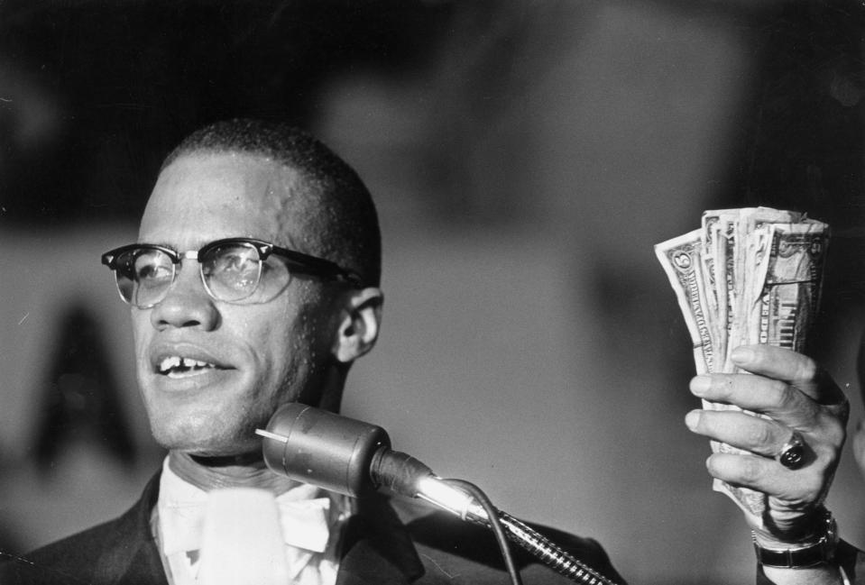 Malcolm X holding a fist full of US currency during a speech at Urline Arena, Washington, DC in 1963.