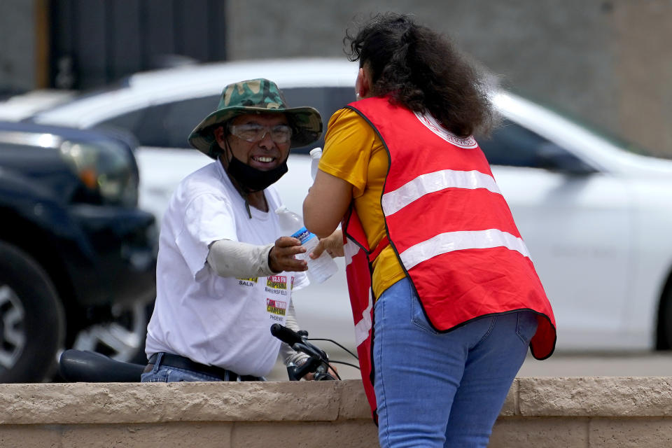 Salvation Army volunteer Soila Arias gives water to a man at their Valley Heat Relief Station, Tuesday, July 11, 2023 in Phoenix. Even desert residents accustomed to scorching summers are feeling the grip of an extreme heat wave smacking the Southwest this week. Arizona, Nevada, New Mexico and Southern California are getting hit with 100-degree-plus Fahrenheit and excessive heat warnings. (AP Photo/Matt York)