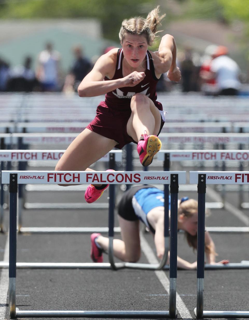 Woodridge's Anna Rorrer clears the final hurdle on her way to victory as Ravenna's Avonlea Jefferson falls during the girls 100-meter hurdles at the Division II regional meet Saturday at Austintown Fitch.