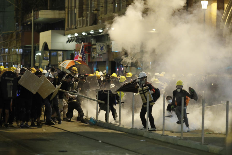 Protesters react to teargas as they confront riot police officers in Hong Kong on Sunday, July 21, 2019. Protesters in Hong Kong pressed on Sunday past the designated end point for a march in which tens of thousands repeated demands for direct elections in the Chinese territory and an independent investigation into police tactics used in previous demonstrations. (AP Photo/Vincent Yu)