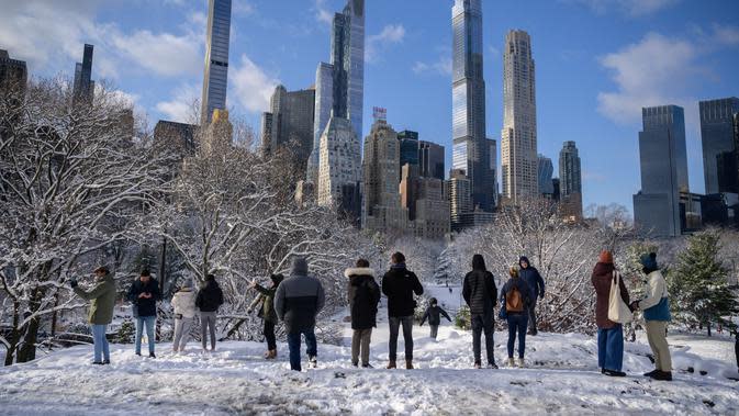 Orang-orang berdiri di viewpoint Central Park setelah badai salju pertama musim dingin 2022 di New York City, Jumat (7/1/2022). Badai musim dingin membawa lebih dari 15 cm salju di bagian timur Amerika Serikat (AS), menutup sekolah, kantor dan jalan-jalan. (Ed JONES / AFP)