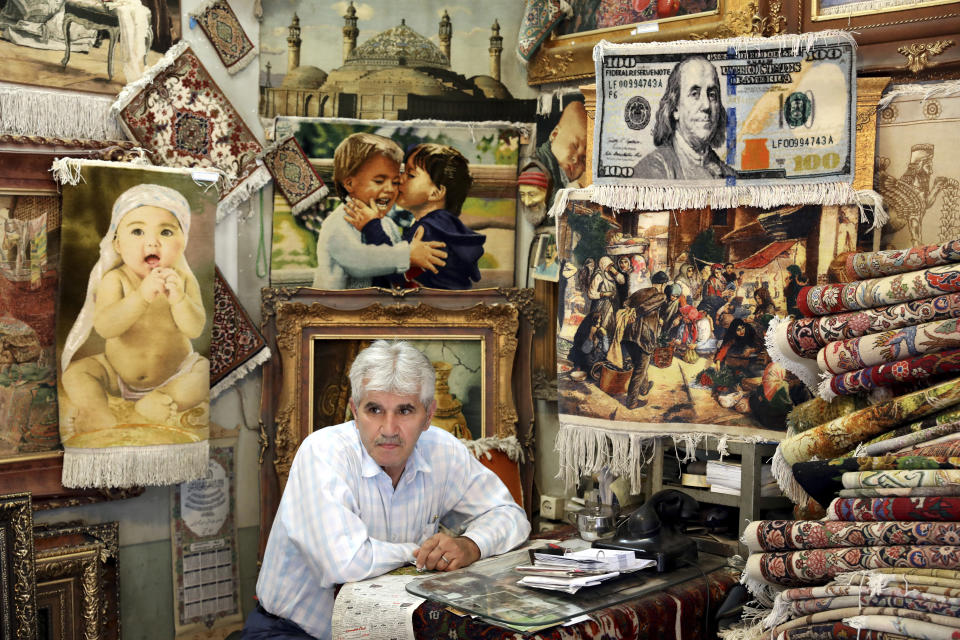 A carpet merchant sits at his shop in the old main bazaar in Tehran, Iran, Tuesday, July 2, 2019. From an English-language teacher hoping for peace to an appliance salesman who applauded Donald Trump as a “successful businessman,” all said they suffered from the economic hardships sparked by re-imposed and newly created American sanctions. (AP Photo/Ebrahim Noroozi)