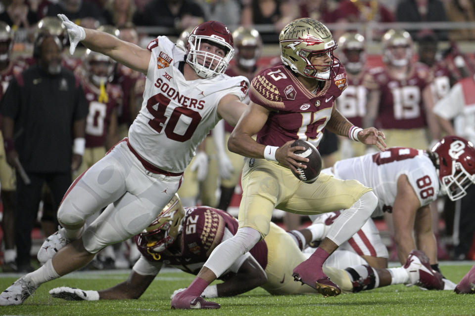 Florida State quarterback Jordan Travis (13) scrambles away from Oklahoma defensive lineman Ethan Downs (40) during the first half of the Cheez-It Bowl NCAA college football game Thursday, Dec. 29, 2022, in Orlando, Fla. (AP Photo/Phelan M. Ebenhack)