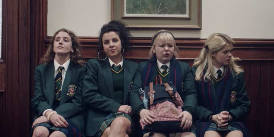 The girls sitting in a hallway in uniform