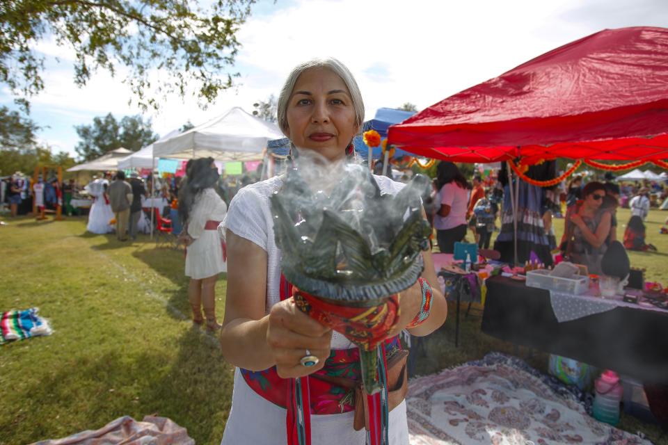 Felicia Cocotzin Ruiz, known as Kitchen Curandera, holds a chalice of smoking herbs at Dia de los Muertos at Indian School Park in Phoenix on Sunday, Oct. 24, 2021.