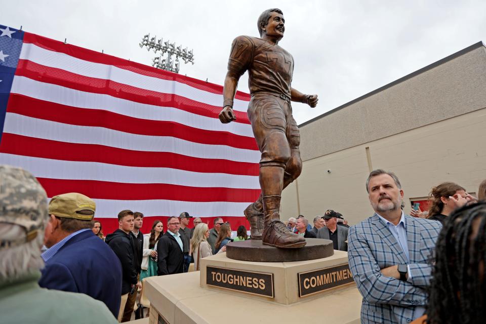 Bob Kalsu Jr. stands under the statue of his father, Robert Kalsu, after a ceremony Friday afternoon at Robert Kalsu Stadium in Del City.