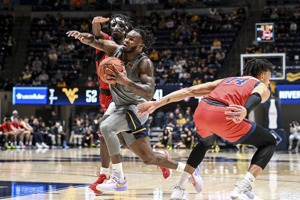 West Virginia guard Joe Toussaint, second from left, is fouled by Stony Brook guard Toby Onyekonwu, left, during the second half of an NCAA college basketball game Thursday, Dec. 22, 2022, in Morgantown, W.Va. (William Wotring/The Dominion-Post via AP)