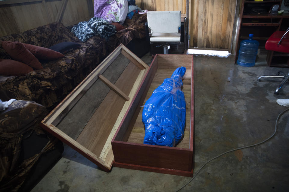 Corazona Pena's body lies in a coffin, wrapped in plastic by a Peruvian COVID-19 specialized government team in Pucallpa, in Peru's Ucayali region, Tuesday, Sept. 29, 2020. As Peru grapples with one the world's worst virus outbreaks, another epidemic is starting to raise alarm: Dengue. (AP Photo/Rodrigo Abd)
