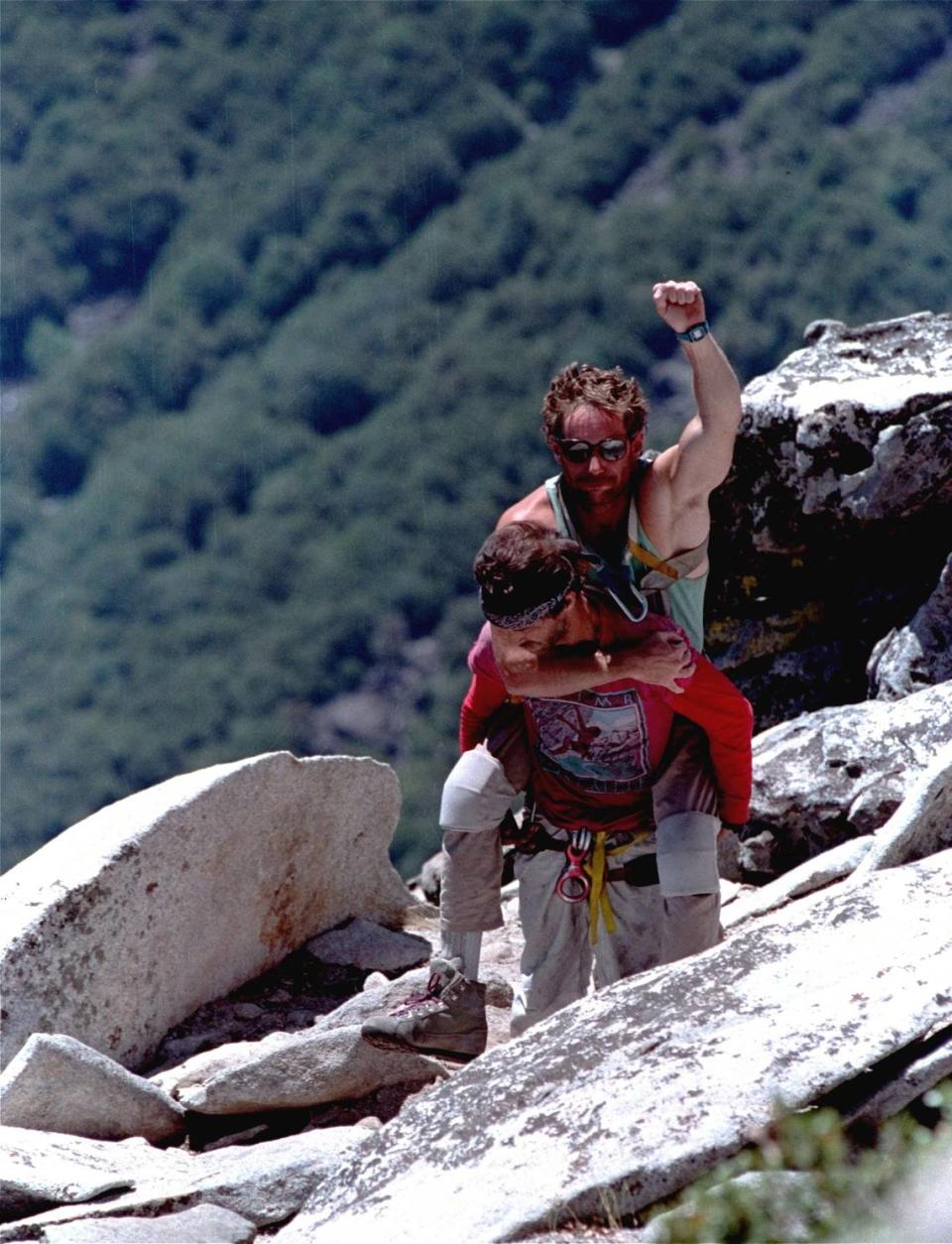 On the back of his climbing partner Mike Corbett, paraplegic rock climber Mark Wellman gives a salute July 26, 1989 after reaching the summit of El Capitan in Yosemite National Park.