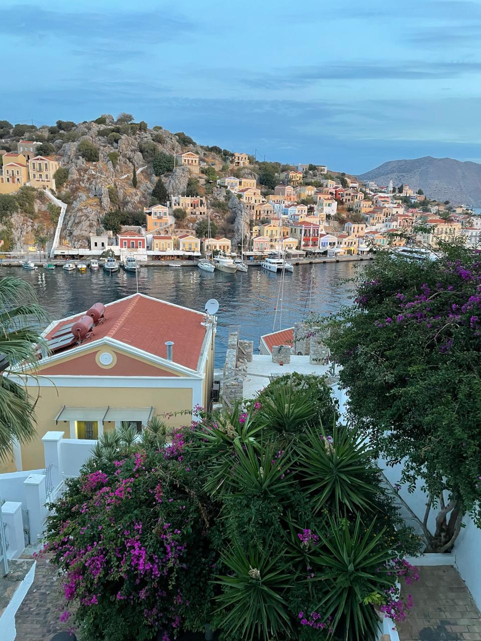 Colorful houses built into a mountain on the water. There are boats docked in the water.