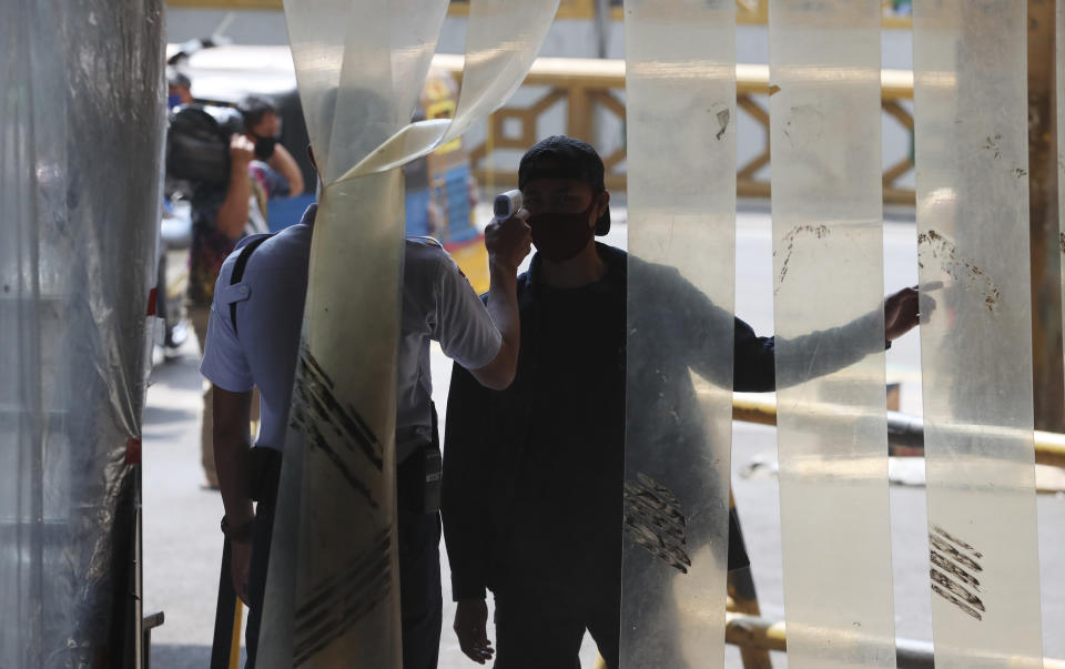 A security guard checks the body temperature of a men before entry a market, amid coronavirus outbreak in Jakarta, Indonesia Tuesday, June 30, 2020.(AP Photo/Achmad Ibrahim)