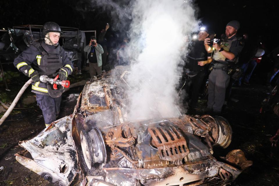 Firefighters put out a fire on a destroyed car (Anadolu via Getty Images)