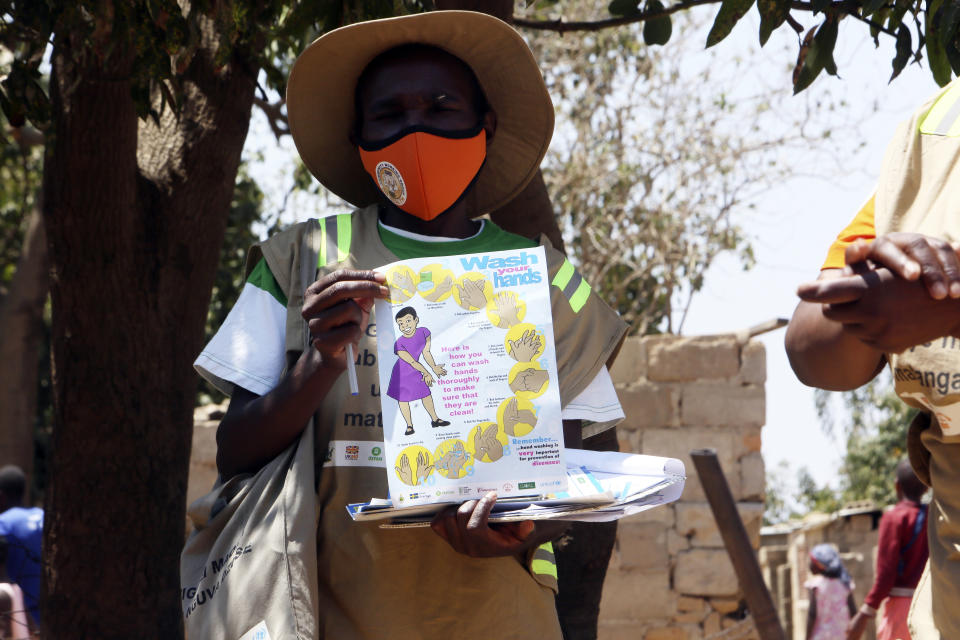 A community health worker holds a pamphlet during a COVID-19 awarness campaign in Chitungwiza on the outskirts of Harare, Wednesday, Sept. 23, 2020. As Zimbabwe's coronavirus infections decline, strict lockdowns designed to curb the disease are being replaced by a return to relatively normal life. The threat has eased so much that many people see no need to be cautious, which has invited complacency. (AP Photo/Tsvangirayi Mukwazhi)