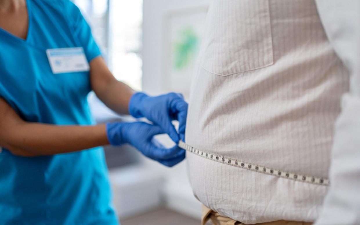 A patient has their stomach measured by a doctor