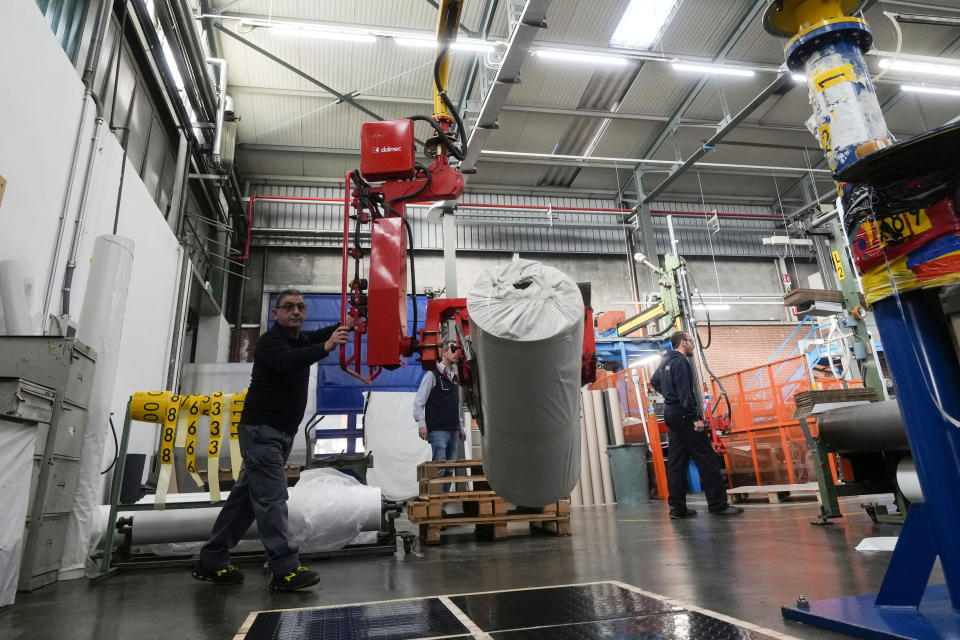 A worker moves a packed final surface of an athletics track, at the Mondo factory, in Alba, northern Italy, Wednesday, March 13, 2024. The athletics track for the upcoming Paris Olympics is being produced by the Mondo company at its factory in northern Italy. The track is made in portions, rolled up and then will be transported to the Stade de France, where it will be installed over the next month. (AP Photo/Luca Bruno)