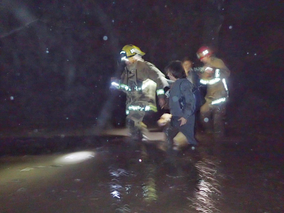 Emergency personnel escort people from flood waters.