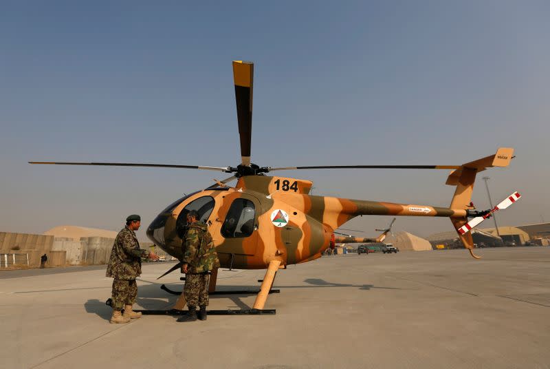 Members of the Afghan Air Force crew stand next to a helicopter at the military airport in Kabul