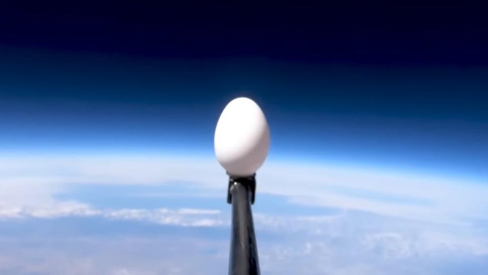 An egg on a black pole in space with the Earth in the background