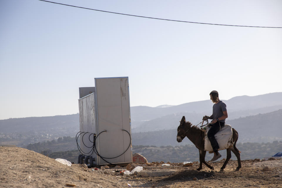 An Israeli settler rides a donkey in the recently established wildcat outpost of Eviatar near the northern Palestinian West Bank city of Nablus, Monday, June 28, 2021. Palestinians say the outpost was established on private farmland. Israeli media said Monday that the government was working on reaching a compromise with the settlers that would see the outpost evacuated in the coming days. (AP Photo/Ariel Schalit)