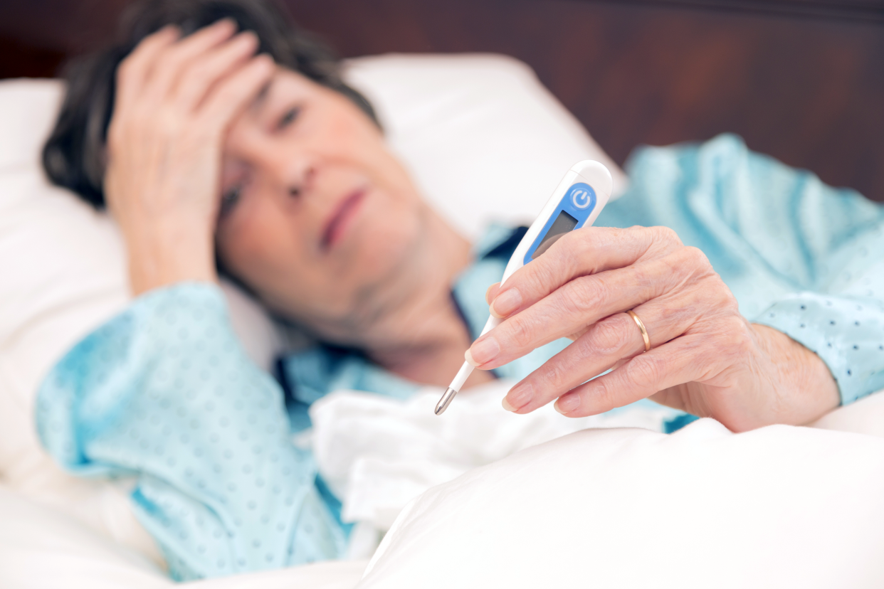 Older woman in bed taking her temperature