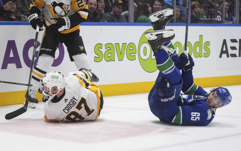 Vancouver Canucks' Ilya Mikheyev, right, is upended by Pittsburgh Penguins' Sidney Crosby during the third period of an NHL hockey game Tuesday, Feb. 27, 2024, in Vancouver, British Columbia. (Darryl Dyck/The Canadian Press via AP)